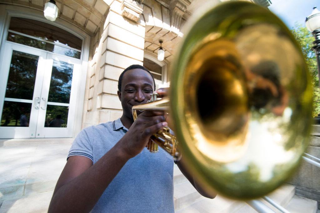 Music student playing trumpet in front of The Conserve